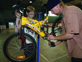 In this KingstonThis Week file photo, Curtis Longmire, 11, assists Michael Pomery, a volunteer with Yellow Bike Action Community Bike Shop, as he repairs the youngster’s bicycle during a spring tune-up at the Wally Elmer Neighbourhood Centre. Recently, Yellow Bike found a new home within the Kingston Memorial Centre with the help of the City of Kingston.        Rob Mooy-Kingston This Week