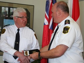 Mike Reid, the communications supervisor with the dispatch in Timmins.Reid, left, is retiring after more than 35 years with the service. On Monday, he was presented a retirement badge from Timmins Police Chief John Gauthier and given warm send-off by the Timmins Police Services Board.