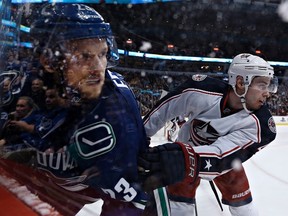 Columbus Blue Jackets' John Moore (R) pushes Vancouver Canucks' Alexander Edler into the boards during the first period of their NHL hockey game in Vancouver, British Columbia March 26, 2013. (REUTERS)