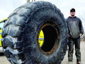 Chris Borden of Vanzuylen Alignment and Tire Service stands Wednesday beside a loader tire, one of the sizes included in a new tire eco-fee. (DARCY CHEEK/The Recorder and Times)