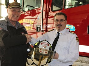 Bert Weeda (left) turning over his helmet to Fire Chief, Richard Vallee, after 40 years of volunteering as a firefighter for Cochrane.