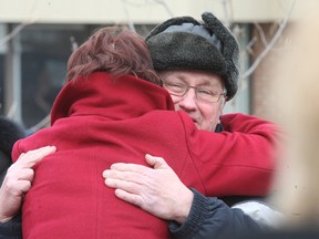 Donald Benoit, whose wife Claudette was killed Wednesday in a hit and run on Wyld Street, is embraced by Paulette Louiseize during a service near where she was struck by a car.