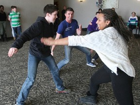Cameron Taylor, left, avoids a 'ninja' touch attempt by Regan Jackson, right, as Me to We facilitator Rob Palmer, centre, leads a team-building exercise at the Best Western, Thursday. The North Bay Police Service's Teen Healthy Relationship initiative gathered 60 students from area high schools to develop skills to effect positive change in the community.