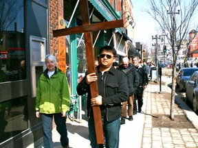 A member of the procession carries the Cross past the Hardwear Company on Main St South on Friday March 29. The walk started at Notre Dame Catholic Church on First Street North and ended at First Presbyterian Church on Fifth Avenue South for Good Friday.