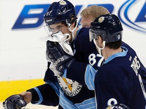 Penguins forward Sidney Crosby is helped off the ice by teammate Pascal Dupuis after being hit in the face with a puck during a game against the Islanders at the Consol Energy Center in Pittsburgh, Pa., March 30, 2013. (JASON COHN/Reuters)