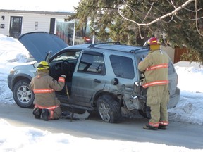 Members of the Portage Fire Department inspect a vehicle after a car struck a parked SUV on Wilkinson Crescent, Monday morning. (ROBIN DUDGEON/THE GRAPHIC/QMI AGENCY)