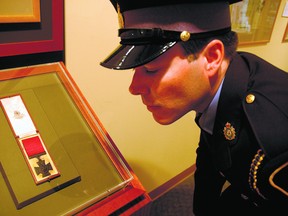 Elgin OPP Auxiliary Const. Marcel Goulet looks at the Victoria Cross awarded Ellis Sifton, when Goulet guarded the medioal during its exhibition in 2011 at Elgin County Museum. PATRICK BRENNAN T-J file photo