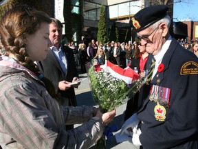 Emily Hyenas, then a student at St. Mary's High School, hands Percy Staight a bouquet of flowers during the closing moments of the 2010 Remembrance Day service in Owen Sound.