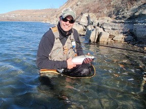 Photo by Scott Pletsch as Dave Levisky holds a Rainbow Trout on the Bow River near the Riversong Community with Glen Eagles in the background last season.