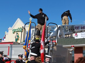 Fort McMurray firefighter Mike Burgess waves to onlookers as he and five other firefighters make the climb up to the Paddy McSwiggins rooftop, where they’ll brave the cold for a four-day campout fundraiser.JORDAN THOMPSON/TODAY STAFF