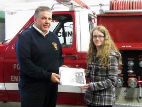 Fire chief Phil Carpenter receives a book on the history of the fire department from Anna-Lisa Blum of the archiving class at Portage Collegiate, Thursday. The class has put together a book on the important fires and community service done by the fire department from the 1950s to the 1980s and made a copy to be donated to the fire hall. (ROBIN DUDGEON/THE GRAPHIC/QMI AGENCY)
