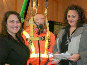 Caroline Mallette, events co-ordinator with the Timmins Construction Association, left, chats with Lisa Kadosa, volunteer with Threads of Life, while standing next to a retrieval mechanism used for rescuing people trapped in confined spaces. The construction association offered support in organizing the third-annual Health and Safety Conference put on by the Timmins Regional Labour-Management Joint Health & Safety Committee at the Timmins Inn & Suites Thursday. Kadosa was one of the keynote speakers at the event.
