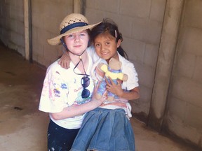 Merideth Brown, 17, takes a break from painting houses in Talnique, La Libertad, El Salvador, to play with a little girl and give her a handmade teddy bear from Gananoque.