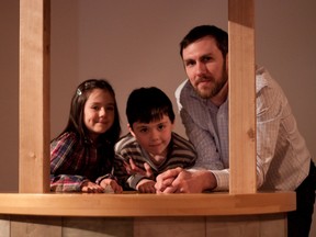 Artist Mitch Robertson and his two kids, Ava, 5, and Olin, 8, lean over a travelling wishing well, the central piece of Roberson's exhibition A Little Bit of Luck, which opened at the Woodstock Art Gallery on Saturday and runs until June 18.  (CODI WILSON/ SENTINEL-REVIEW)