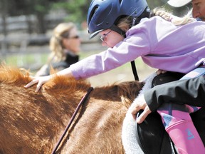 Anya Morgan stretches to reach the horse’s neck during her Rundle Riders session during the 2011 riding season. File photo