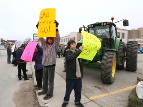 Protesters wave signs at passing motorists during a protest in front of Bruce-Grey-Owen Sound M.P. Larry Miller's Owen Sound constituency office on Tuesday, April 9, 2013. About 70 protesters rallied for a ban on genetically modified alfalfa. (L-R) Nancy Thompson, John Stewart,Tony King.