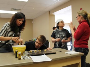 Jeff Isard, second from left, and Yi Min Chung make cookies with assistance from their intervenors Ruth Perez, left, and Marsha Chapman at the Canadian Deafblind Association’s Ontario chapter new resource centre in Paris, which opened to consumers, intervenors and families of the deafblind on Tuesday. MICHAEL PEELING/The Paris Star