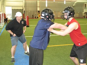 Cornwall Wildcats defensive line coach Charlie Cruickshank (left) watches a drill involving Trevor Lamarche (blue jersey) and Andrew Pidgeon, during a workout at the Benson Centre fieldhouse.
Todd Hambleton staff photo