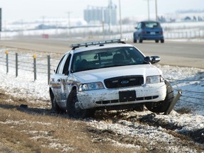 A sheriff and a Carstairs firefighter stand near an immobilized Alberta Sheriff patrol cruiser that sits mangled in the median on Highway 2 northbound, about two kilometres south of Highway 581 around 5:30 p.m., Apr., 8. The Sheriff was allegedly run off the road when a suspected stolen truck hit him. The suspects fled the scene, later and allegedly stole another truck, but were captured shortly after 6:30 p.m.