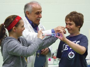 Jayden Weltz, left, and fellow Sacred Heart Elementary School student Jack Buhler, right, discover that electricity flows almost everywhere, even through the human body, as Science Timmins president Antoine Garwah looks on in amusement. The experiment – and many others – was part of Fun With Science which kicked off the 2013 Science Festival's week of activities.