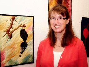 Artist Marcy Horswill poses with a piece of artwork that is currently featured in her exhibit, The Other Side of the Fence, currently up at the Centre for Creative Arts. This particular piece is made with several dead rose hips. (Photo courtesy Stacey Crossley)