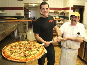 Noele Murano, left, manager of Gino's Pizza and Spaghetti on Princess Street, with Jamie Amorin and their extra-large pizza. (MICHAEL LEA The Whig-Standard)
