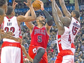 Bulls’ Carlos Boozer tries to drive to the basket while surrounded by Raptors’ Rudy Gay, Quincy Acy and Amir Johnson Friday night. (REUTERS)