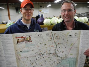 Gregory Boyd, owner of Heritage Lane Produce south of Langton, and Clark Hoskin, manager of tourism and economic development with Norfolk County, show off the latest edition of the Norfolk County's official map and local food guide at the Simcoe Farmers' Market last Thursday. (SARAH DOKTOR Simcoe Reformer)