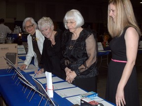 Friends Carol Aragon, left to right, Frances Gottschlich, Alma Yates, and Lisa Dennis look at items up for grabs in the Woodstock and District Developmental Services silent auction during the Woodstock/Oxford Rotary Fish Fry Saturday, April 13, 2013. 
(TARA BOWIE, Sentinel-Review)