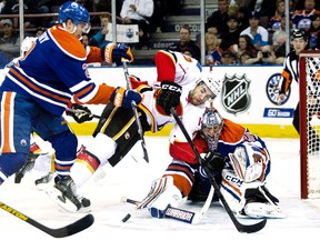 Chatham's T.J. Brodie, centre, of the Calgary Flames is shoved by Edmonton Oilers' Jeff Petry on Saturday in Edmonton. (CODIE MCLACHLAN/QMI Agency)