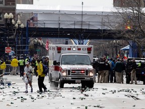 A runner is escorted from the scene after explosions went off at the 117th Boston Marathon in Boston, Massachusetts April 15, 2013. Two explosions hit the Boston Marathon as runners crossed the finish line on Monday, killing at least two people and injuring 23 on a day when tens of thousands of people pack the streets to watch one of the world's best known marathons. (REUTERS/Jessica Rinaldi)