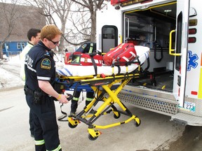 A paramedic pulls out a power stretcher from the back of an ambulance.