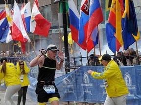 A runner and race officials react to an explosion during the Boston Marathon in Boston on Monday.
