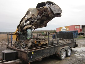 Peter Torensma of Dream Concepts Landscaping & Construction loads a burned-out vehicle onto a trailer as the cleanup at the farm of Bill Heeg west of Jarvis continued on Tuesday. An old barn on the Heeg property burned to the ground Monday after a grass fire spread out of control. (MONTE SONNENBERG Simcoe Reformer)