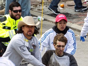 Carlos Arredondo helps first responders tend to the wounded after two explosions occurred along the final stretch of the Boston Marathon on Boylston Street in Boston, Massachusetts, U.S., on Monday, April 15, 2013.