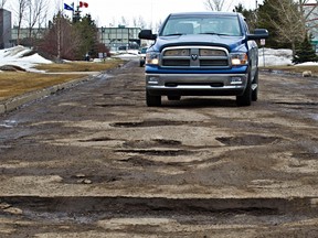 Vehicles navigate a pothole strewn road at 92 Street and 41 Avenue in Edmonton, Alta., on Thursday, April 4, 2013. Codie McLachlan/QMI Agency