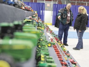 Frank Douglas, left, shows of his collection of toy tractors and farm equipment to Carol Ashton which were on display in the Ag Hall at the Trade Show April 13. Douglas has been collecting for the last 30 years.