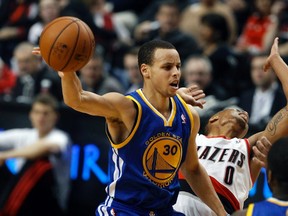 Golden State Warriors point guard Stephen Curry (30) passes as Portland Trail Blazers point guard Damian Lillard (0) defends during the first half of their NBA basketball game in Portland, Oregon, April 17, 2013. (REUTERS/Steve Dipaola)