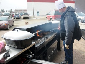 Peace Wapiti Academy ActiParent Dan George cooks burgers and hotdogs on a new grill donated to the school by Accu-Fab Custom Metal Works. (Aaron HInks/Daily Herald-Tribune)