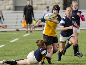 Napanee Golden Hawks’ Ashton Barton passes the ball while being tackled by the Kingston Blues’ Erin Fleming during the first girls rugby game of the Kingston Area Secondary Schools Athletic Association season at Nixon Field on Thursday. Napanee won 73-0. (Julia McKay/For The Whig-Standard)