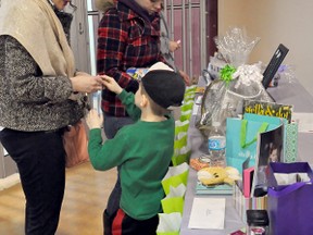 Ashley Hewins, son Christian, 5, and sister-in-law Paige Hewins put their tickets into the draw for a variety of prizes at the Ukrainian Nursery School craft sale at Portage Mall on Saturday. The event was organized by Jenna Bulachowski to raise money for the school's major renovation project at Trinity United Church. (CLARISE KLASSEN/PORTAGE DAILY GRAPHIC/QMI AGENCY)