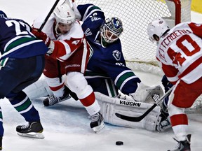 Vancouver Canucks goalie Cory Schneider (centre) stops the puck from both Detroit Red Wings Justin Abdelkader (left) and Henrik Zetterberg during Saturday's game at Rogers Arena. REUTERS