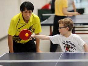 Former Philippine national team member and coach Henberd Ortalla works with GP Table Tennis Club member Austin Boyd, 7, at the free table tennis clinic held by the club in the Eastlink Centre, Saturday. (Aaron Hinks/Daily Herald-Tribune)