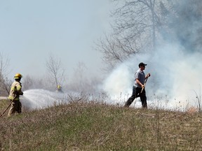 County of Brant firefighters hose down a brush fire that got out of control in an empty lot where trees were being cut down on Sharp Road in Paris on Monday, April 22, 2013 after 1:30 p.m. Others threw dirt on the fire. The blaze was out in a matter of minutes. MICHAEL PEELIING/The Paris Star/QMI Agency