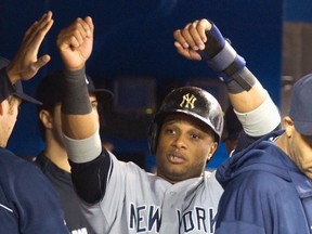 New York Yankees' Robinson Cano is congratulated in the dugout after scoring the Yankees third run on a bases loaded walk by Toronto Blue Jays pitcher Josh Johnson in the fifth inning of their American League MLB baseball game in Toronto April 21, 2013. (REUTERS/Fred Thornhill)