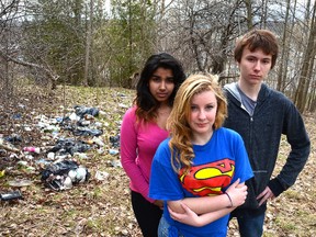 Students from Denise Gariepy's Grade 9 religion class stand in front of broken garbage bags on the hill below the school on Tuesday. The class was taking part in an Earth Day cleanup on Monday when they came across the garbage. Pictured are, from left, Afshana Miah, Drew Millson and Luke Edwards. Rob Gowan, The Sun Times