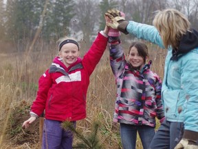 Springbank Public School students Kassidy Norris, left, with Brooke Martin and teacher Kris McMahon celebrate their tree planting efforts at Burgess Park on Wednesday. (HEATHER RIVERS, Sentinel-Review)