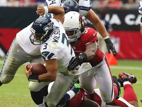Seattle Seahawks quarterback Russell Wilson gets wrapped up by the Arizona Cardinals' Quentin Groves during the second half of their NFL football game in Phoenix, Arizona September 9, 2012. (REUTERS)