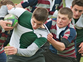 Assumption defender Luke Saunders (right) latches on to St. John's ball carrier Zach Dawson during a high school junior boys rugby match on Thursday at the Tollgate Tech field. (BRIAN THOMPSON, The Expositor)