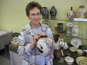 Longtime Brantford Potters' Guild member Suzanne Welsby holds an elegant pot she created using wire, copper sulphate, salt and a sawdust firing technique at the group's annual spring pottery sale at Mohawk College. (SUSAN GAMBLE, The Expositor)